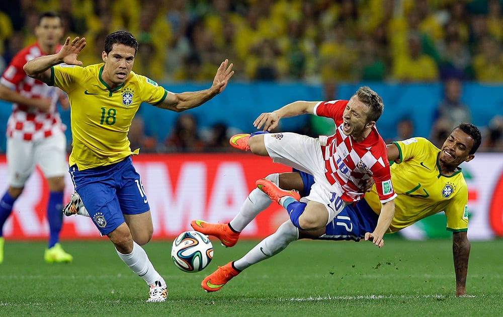 Croatia's Luka Modric, centre, is fouled by Brazil's Luiz Gustavo, right, during the group A World Cup soccer match between Brazil and Croatia, the opening game of the tournament, in the Itaquerao Stadium in Sao Paulo, Brazil.