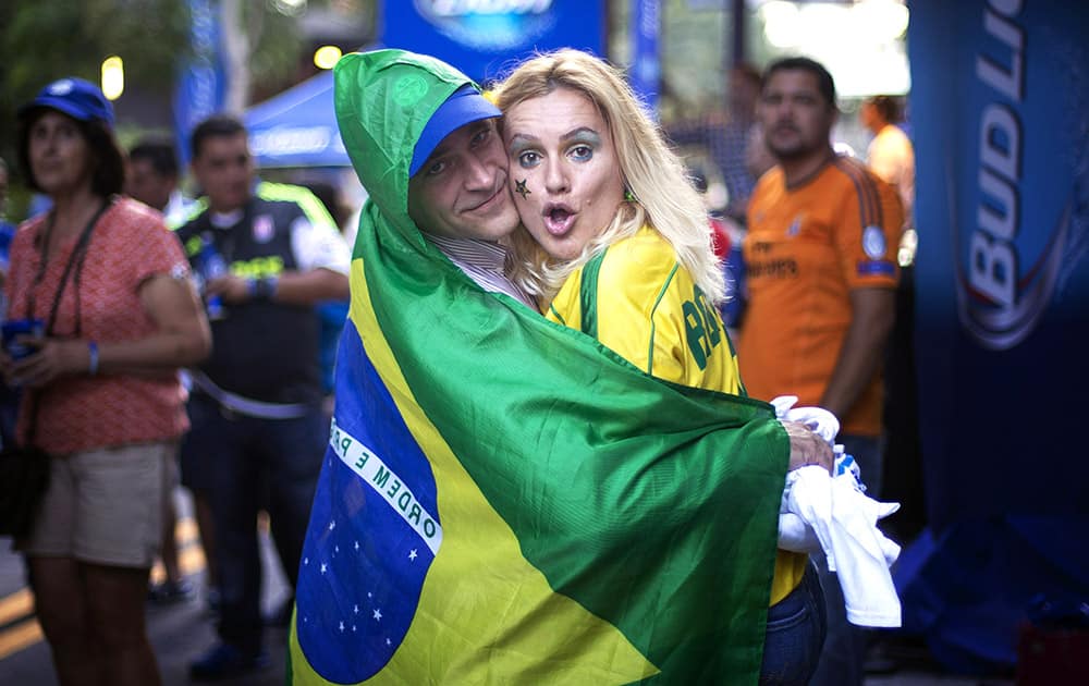 Brazilian soccer fans Ray Zacaro, left, and Adriana Strauss dance after a World Cup soccer match between Brazil and Croatia, at the Kukaramakara cafe block party in Miami.