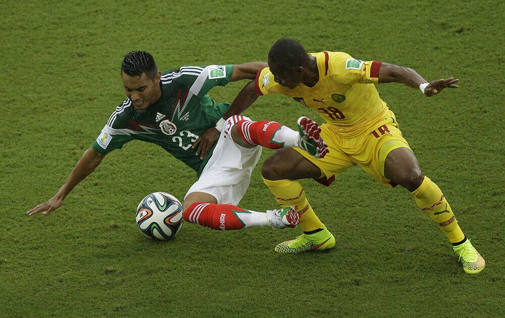 Mexico's Jose Juan Vazquez, left, is tackled by Cameroon's Eyong Enoh during the group A World Cup soccer match between Mexico and Cameroon in the Arena das Dunas in Natal, Brazil