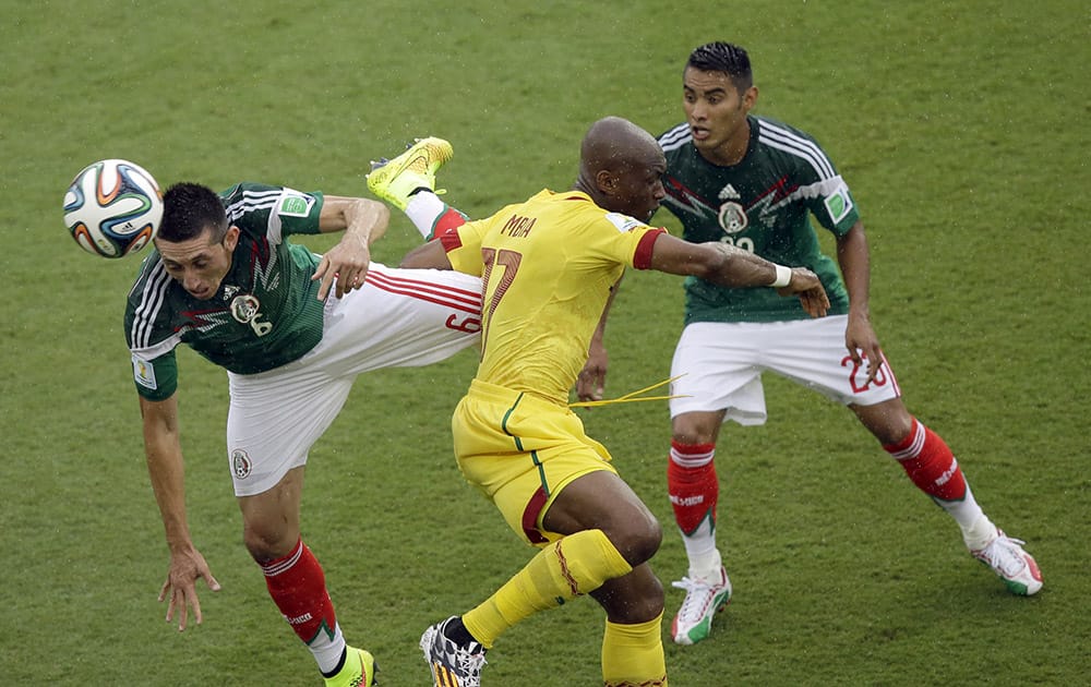 Mexico's Hector Herrera, left, and Mexico's Jose Juan Vazquez, right, fight for the ball with Cameroon's Stephane Mbia during the group A World Cup soccer match between Mexico and Cameroon in the Arena das Dunas in Natal, Brazil.