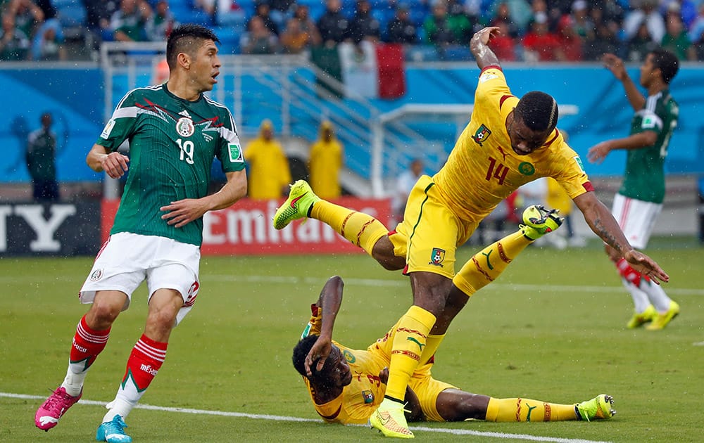 Cameroon's Aurelien Chedjou, top, right, and Cameroon's Nicolas N’Koulou collide as Mexico's Oribe Peralta looks on during the group A World Cup soccer match between Mexico and Cameroon in the Arena das Dunas in Natal, Brazil.