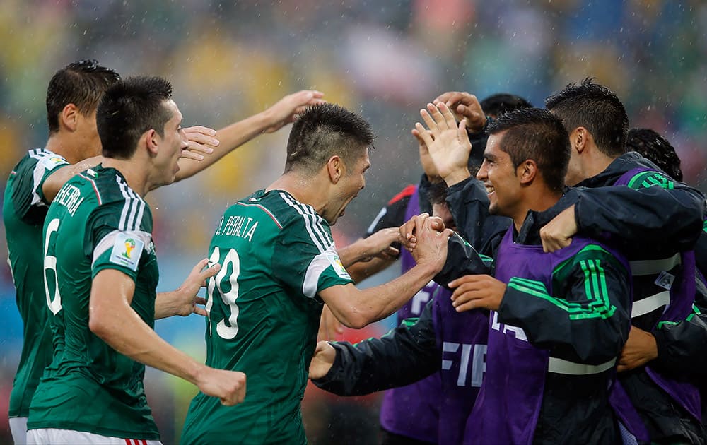 Mexico's Oribe Peralta, center, is congratulated by teammates after his goal during the second half of the group A World Cup soccer match between Mexico and Cameroon in the Arena das Dunas in Natal, Brazil