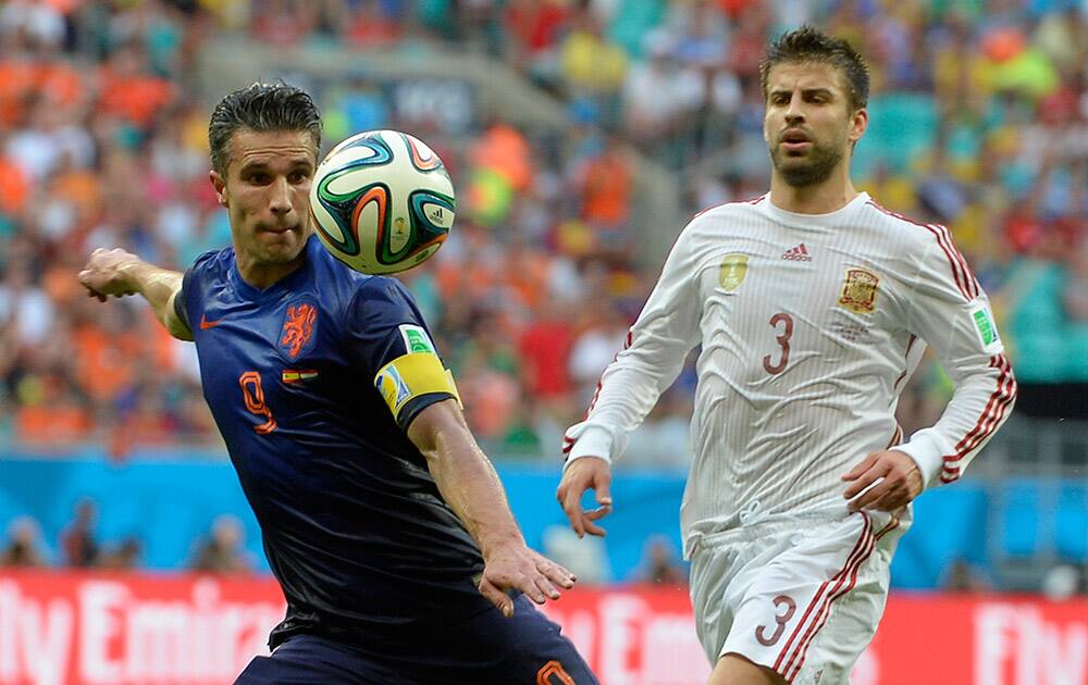 Netherlands' Robin van Persie, left, prepares to take a shot watched by Spain's Gerard Pique during the group B World Cup soccer match between Spain and the Netherlands at the Arena Ponte Nova in Salvador, Brazil.