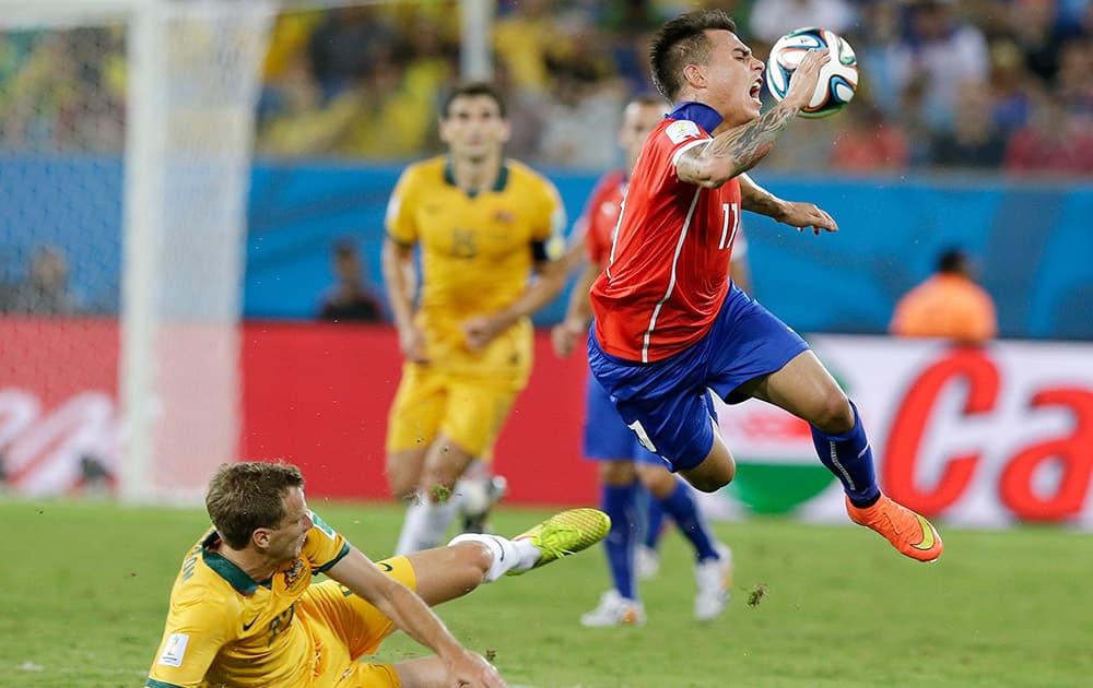 Australia's Alex Wilkinson, left, trips up Chile's Eduardo Vargas (11) during the first half of the group B World Cup soccer match between Chile and Australia in the Arena Pantanal in Cuiaba, Brazil.