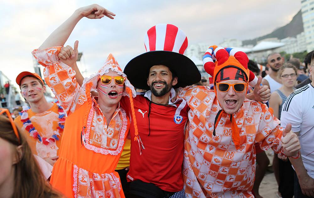 Dutch soccer fans pose for a photo with a Chilean soccer fan, center, while watching the live broadcast of the World Cup match between Spain and the Netherlands, inside the FIFA Fan Fest area on Copacabana beach in Rio de Janeiro, Brazil.