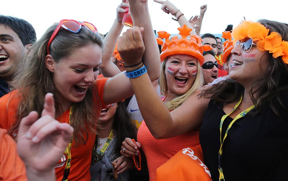 Netherlands soccer fans celebrates their team's goal against Spain as they watch the World Cup match inside the FIFA Fan fest area on Copacabana beach in Rio de Janeiro, Brazil.