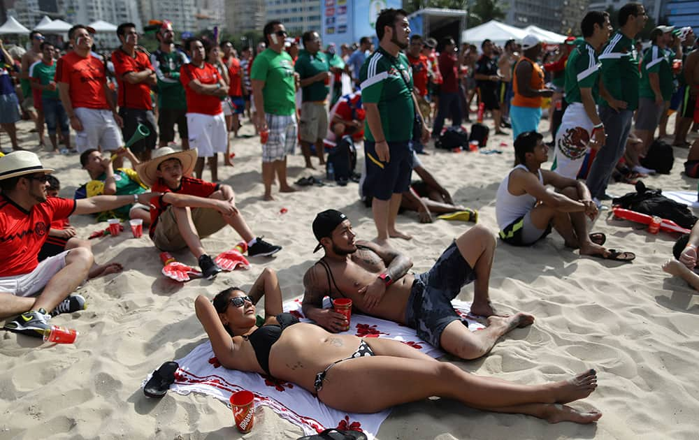 A Mexico soccer fan sunbathes as she watches her team's World Cup match with Cameroon inside the FIFA Fan fest area on Copacabana beach, in Rio de Janeiro, Brazil.