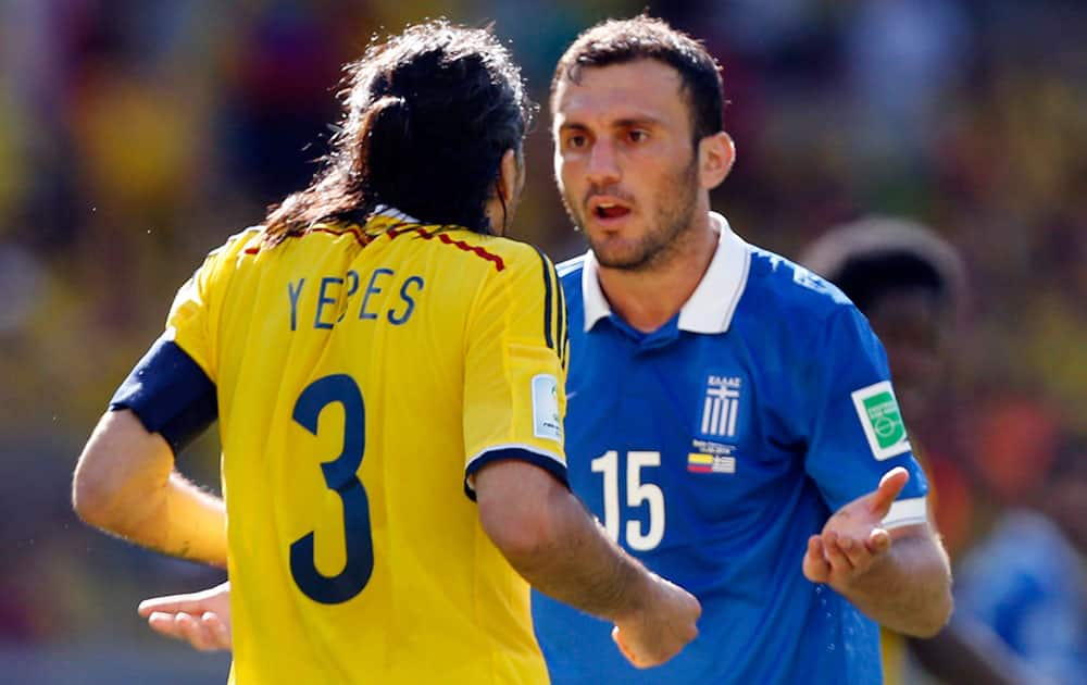 Colombia's Mario Yepes, left, and Greece's Vasilis Torosidis have a difference of opinion during the group C World Cup soccer match between Colombia and Greece at the Mineirao Stadium in Belo Horizonte, Brazil.