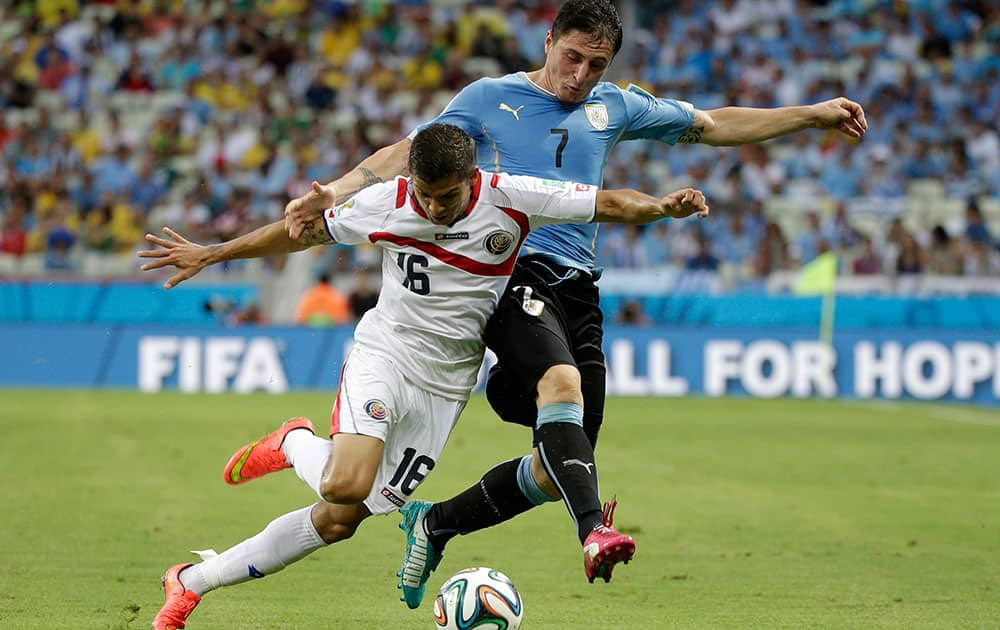 Costa Rica's Cristian Gamboa, left, is sent tumbling by a challenge from Uruguay's Cristian Rodriguez during the group D World Cup soccer match between Uruguay and Costa Rica at the Arena Castelao in Fortaleza, Brazil.