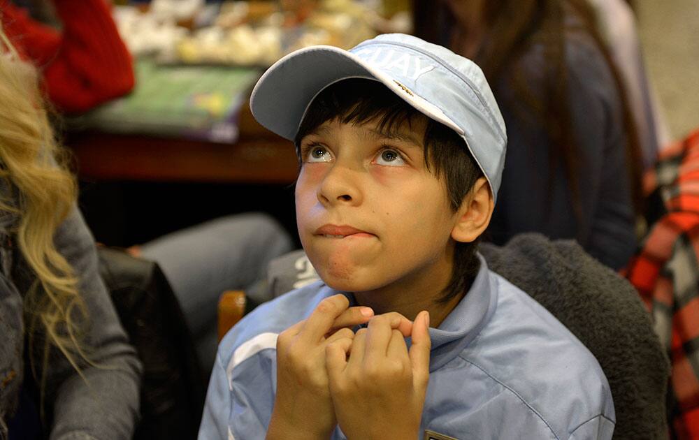 A fan of Uruguay's national soccer team crosses his fingers for good luck as he watches the World Cup match between Costa Rica and Uruguay in downtown in Montevideo, Uruguay.