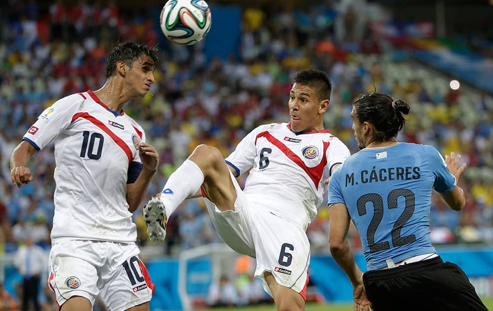 Costa Rica's Bryan Ruiz, left, and Costa Rica's Oscar Duarte clear the ball from Uruguay's Martin Caceres during the group D World Cup soccer match between Uruguay and Costa Rica at the Arena Castelao in Fortaleza, Brazil.