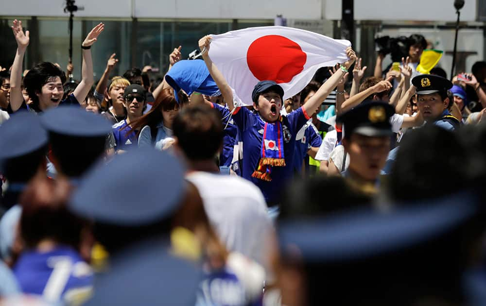 Japanese soccer fans gather on a crossroad following the group C World Cup soccer match between Japan and Ivory Coast, at the Tokyo's Shibuya shopping district.