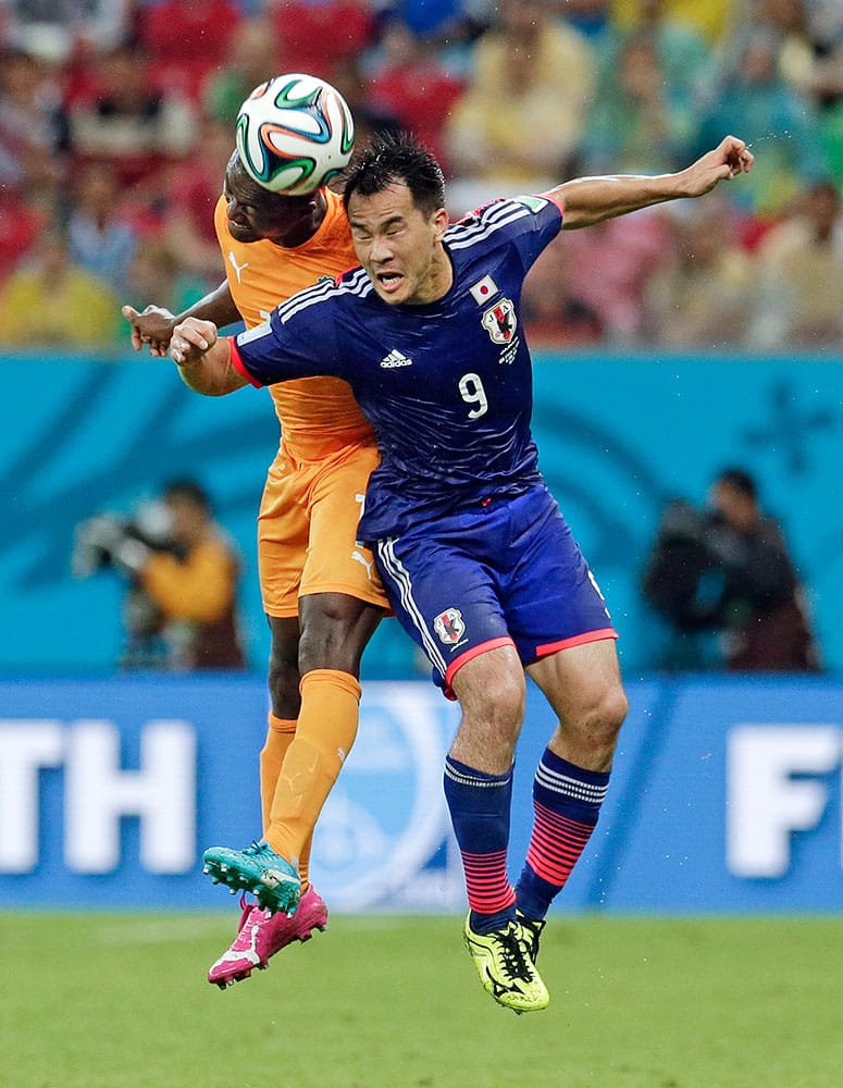 Japan's Shinji Okazaki (9) heads the ball with Ivory Coast's Constant Djakpa, left, during the group C World Cup soccer match at the Arena Pernambuco in Recife, Brazil.