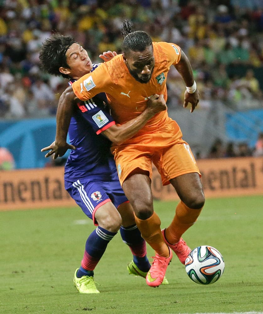 Japan's Masato Morishige, left, tries to hold Ivory Coast's Didier Drogba, right, during the group C World Cup soccer match at the Arena Pernambuco in Recife, Brazil.