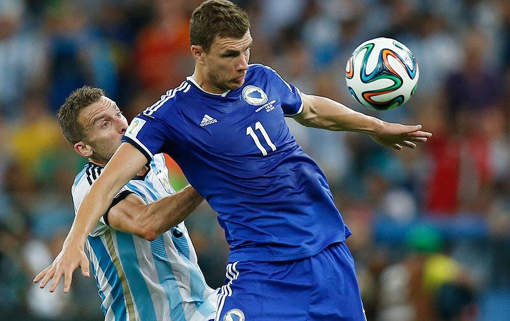 Bosnia's Edin Dzeko shields the ball from Argentina's Hugo Campagnaro during the group F World Cup soccer match between Argentina and Bosnia at the Maracana Stadium in Rio de Janeiro, Brazil.