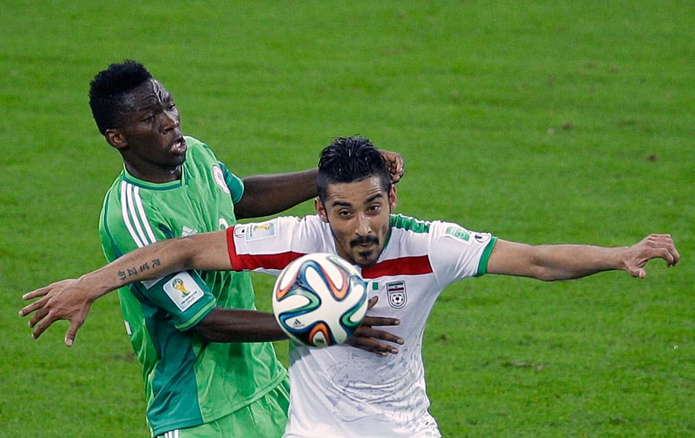 Nigeria's Kunle Odunlami, left, and Iran's Reza Ghoochannejhad challenge for the ball during the group F World Cup soccer match between Iran and Nigeria at the Arena da Baixada in Curitiba, Brazil.