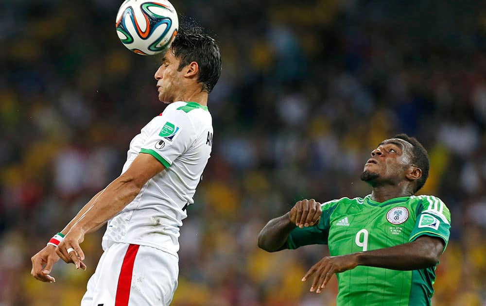 Iran's Amirhossein Sadeghi heads the ball in front of Nigeria's Emmanuel Emenike during the group F World Cup soccer match between Iran and Nigeria at the Arena da Baixada in Curitiba, Brazil.