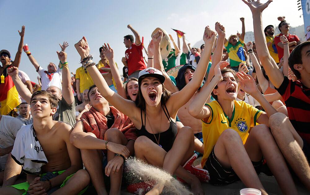 Soccer fans, many supporting Germany, raise their arms and cheer at the FIFA Fan Fest area on Copacabana beach, after Thomas Mueller scored Germany's fourth goal against Portugal in Rio de Janeiro, Brazil, during Germany's World Cup soccer match with Portugal.