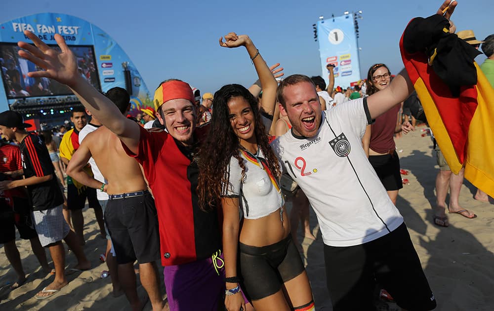 Soccer fans pose for a photo with a woman whose body is painted with Germany's national soccer team colors, at the end of a live broadcast of the World Cup match between Portugal and Germany, inside the FIFA Fan Fest area on Copacabana beach, in Rio de Janeiro, Brazil.