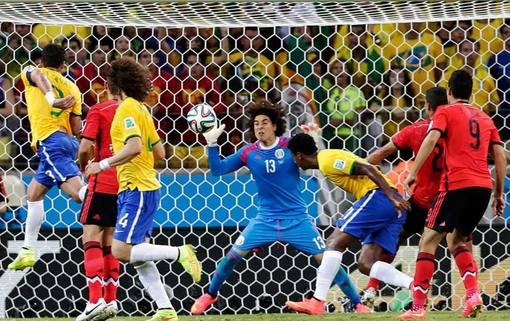 Mexico's goalkeeper Guillermo Ochoa (13) bats the ball away after a header by Brazil's Fred, left, during the group A World Cup soccer match between Brazil and Mexico at the Arena Castelao in Fortaleza, Brazil.