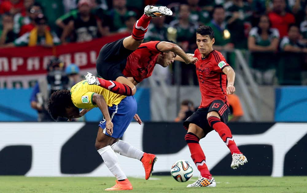 Brazil's Willian, left, challenges Mexico's Marco Fabian, center, and Hector Moreno during the group A World Cup soccer match between Brazil and Mexico at the Arena Castelao in Fortaleza, Brazil.