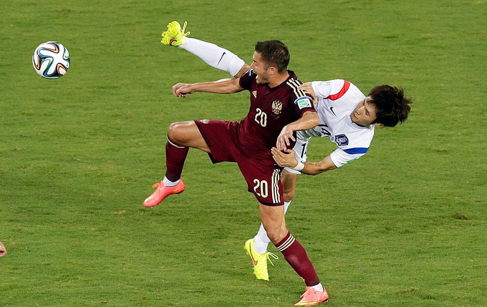 Russia's Viktor Fayzulin, left, and South Korea's Han Kook-young, right, challenge for the ball during their group H World Cup soccer match at the Arena Pantanal in Cuiaba, Brazil.