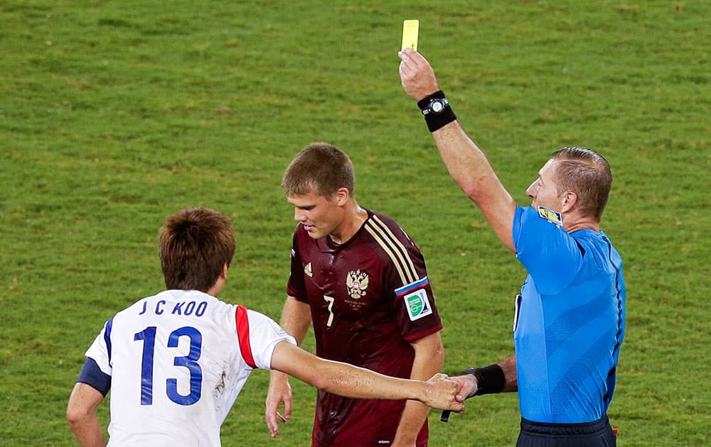 Referee Nestor Pitana, from Argentina, right, books South Korea's Koo Ja-cheol (13) during the group H World Cup soccer match between Russia and South Korea at the Arena Pantanal in Cuiaba, Brazil.