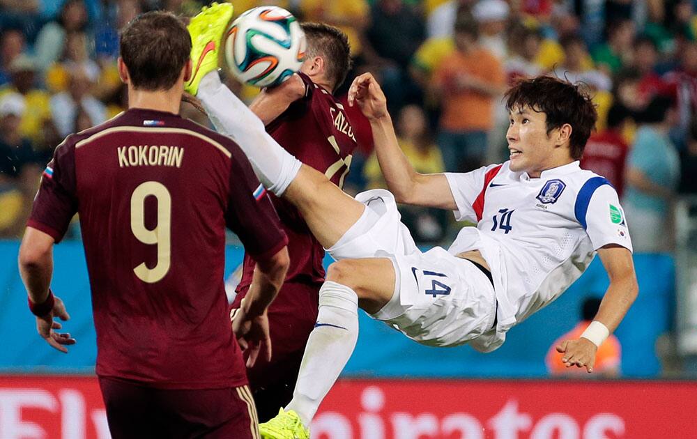 South Korea's Hong Jeong-ho, right, scissor kicks the ball between Russia's Viktor Fayzulin and Alexander Kokorin (9) during the group H World Cup soccer match between Russia and South Korea at the Arena Pantanal in Cuiaba, Brazil.