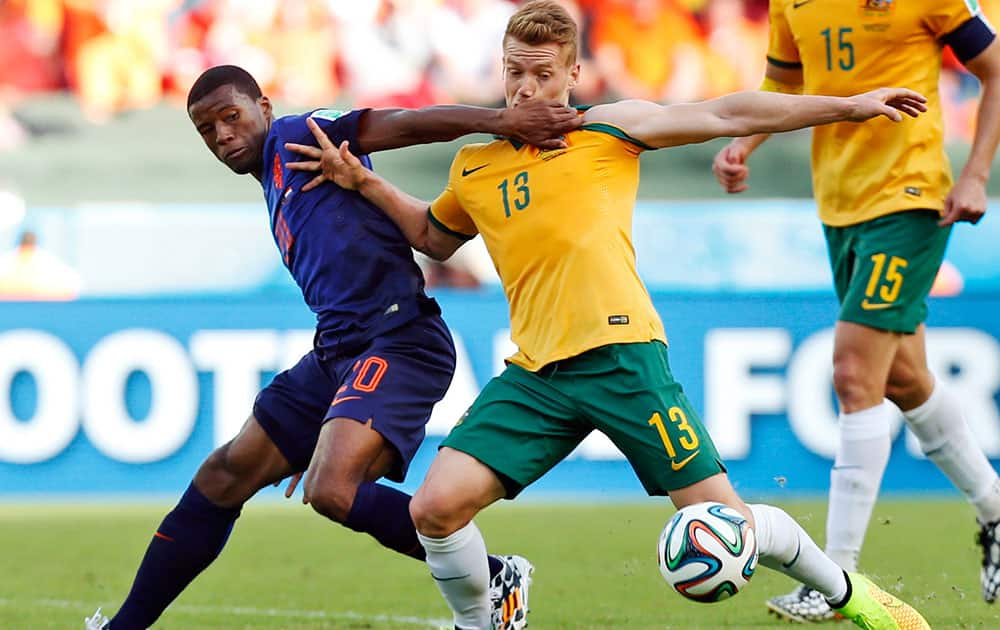 Netherlands' Georginio Wijnaldum, left, grapples with Australia's Oliver Bozanic during the group B World Cup soccer match between Australia and the Netherlands at the Estadio Beira-Rio in Porto Alegre, Brazil.