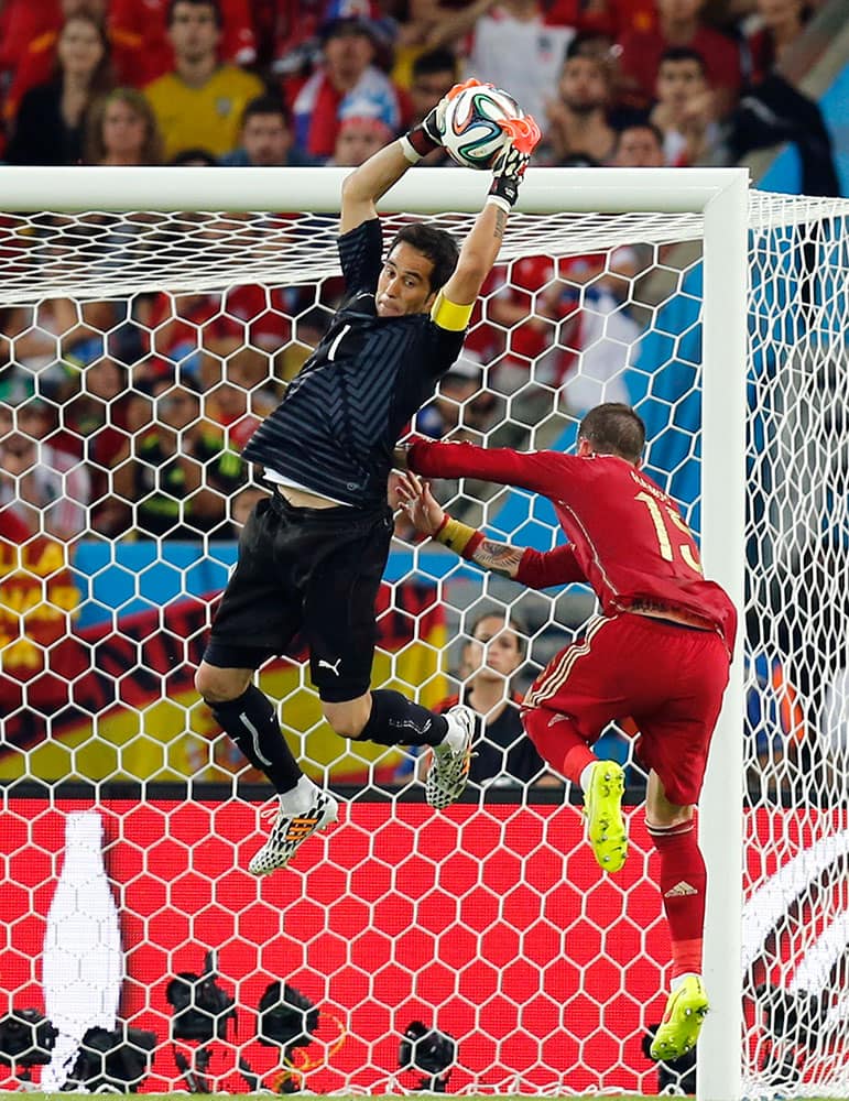 Chile's goalkeeper Claudio Bravo makes a save against Spain's Sergio Ramos during the group B World Cup soccer match between Spain and Chile at the Maracana Stadium in Rio de Janeiro, Brazil.