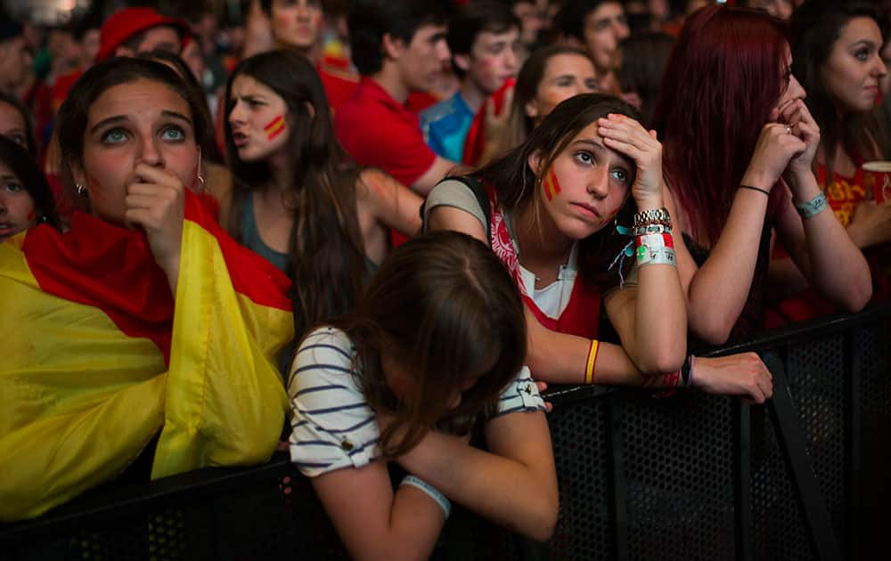 Spanish soccer fans gesture as they watch on a giant display the World Cup soccer match between Spain and Chile, in Madrid, Spain.