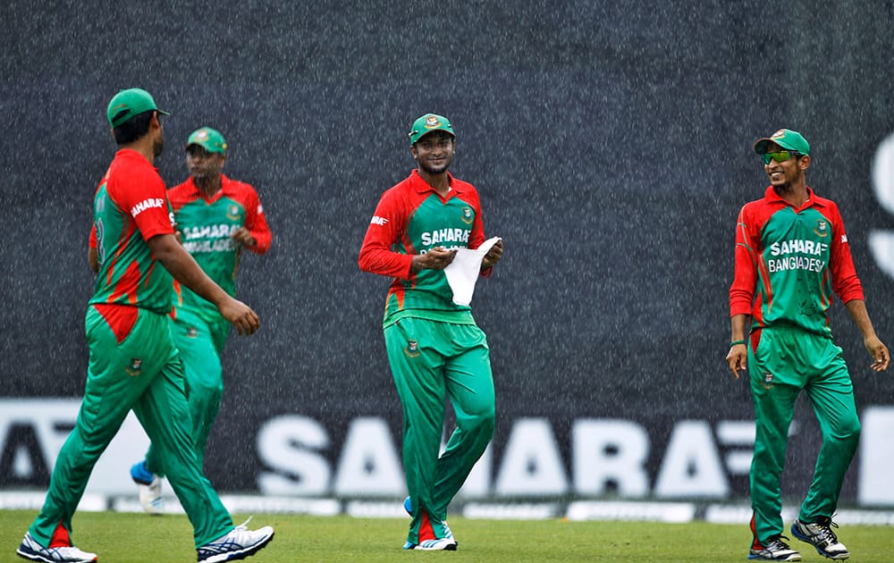 Bangladesh's Shakib Al Hasan, center, Nasir Hossain, right and Tamim Iqbal, left walk back to the pavilion after their third one-day International cricket match against India is interrupted due to rain in Dhaka.