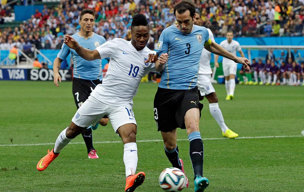 England's Raheem Sterling, left, is challenged by Uruguay's Diego Godin during the group D World Cup soccer match between Uruguay and England at the Itaquerao Stadium in Sao Paulo