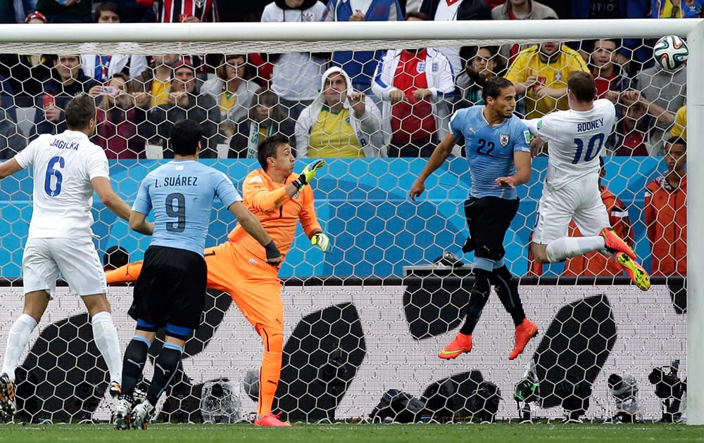 England's Wayne Rooney hits the goal post with a header defended by Uruguay's Martin Caceres during the group D World Cup soccer match between Uruguay and England at the Itaquerao Stadium in Sao Paulo, Brazil.