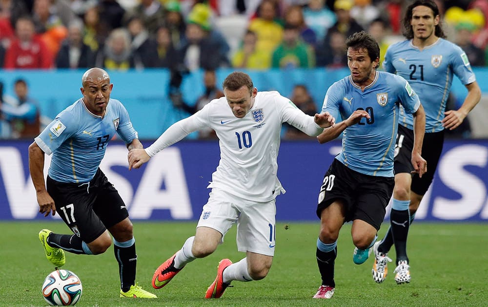 England's Wayne Rooney, second left, takes on the Uruguay defense during the group D World Cup soccer match between Uruguay and England at the Itaquerao Stadium in Sao Paulo, Brazil.