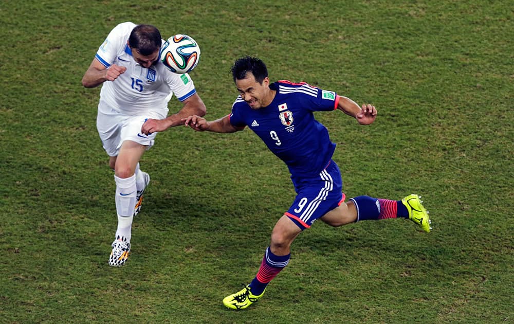 Japan's Shinji Okazaki, right, and Greece's Vasilis Torosidis go for a header during the group C World Cup soccer match between Japan and Greece at the Arena das Dunas in Natal, Brazil.