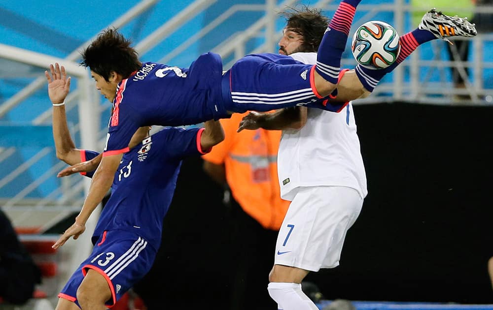 Japan's Atsuto Uchida, center, flies over teammate Yoshito Okubo, left, and Greece's Giorgos Samaras as he tries to clear the ball during the group C World Cup soccer match between Japan and Greece at the Arena das Dunas in Natal, Brazil.