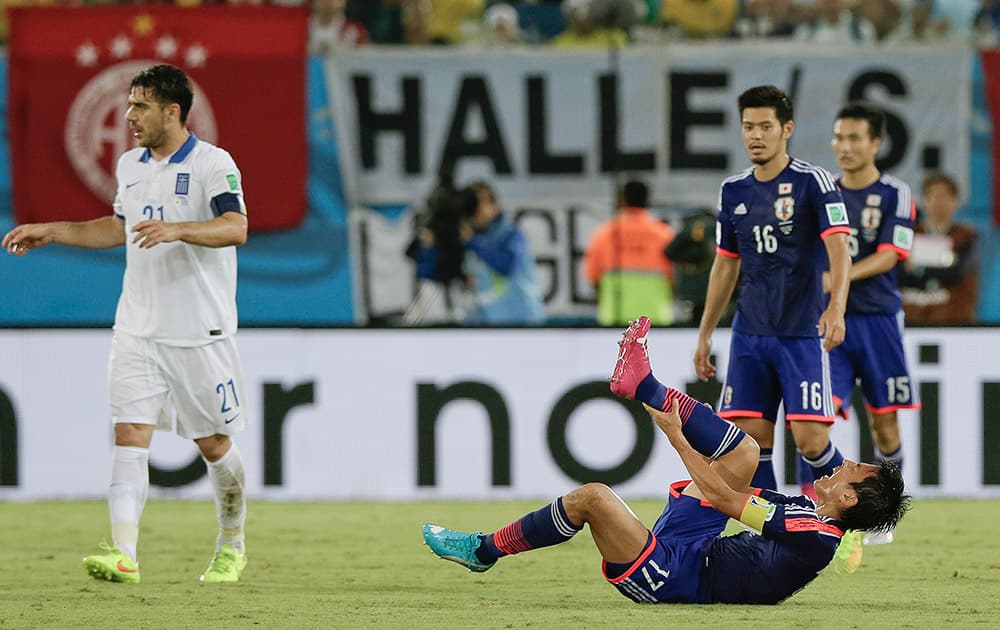 Greece's Kostas Katsouranis, left, walks away after fouling Japan's Makoto Hasebe, right, during the group C World Cup soccer match between Japan and Greece at the Arena das Dunas in Natal.