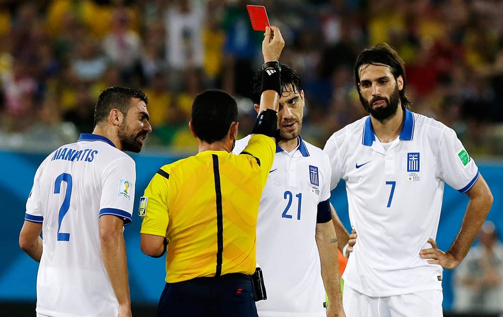 Greece's Kostas Katsouranis (21), Giannis Maniatis (2) and Giorgos Samaras (7) talk with referee Joel Aguilar from El Salvador as he ejects Katsouranis from the match during the group C World Cup soccer match between Japan and Greece at the Arena das Dunas in Natal, Brazil.