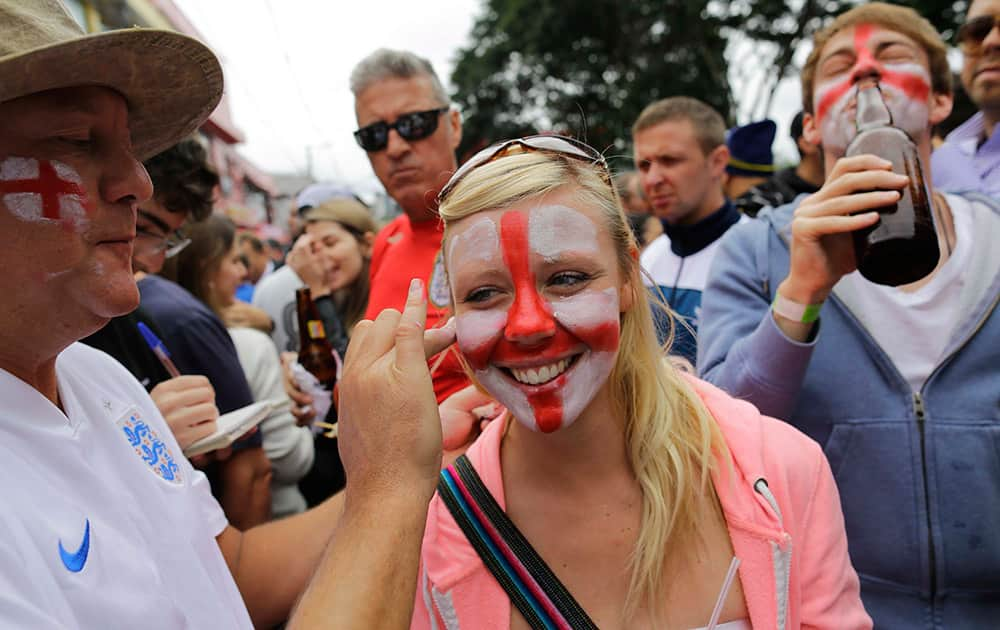 A soccer fan stands still as her face is painted the team colors of the British national soccer team, near Arena Corinthians stadium, before the start of the group D World Cup soccer match between Uruguay and England in Sao Paulo.