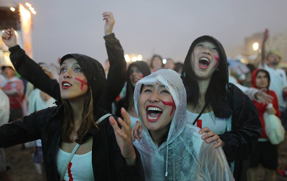 Soccer fans wearing England's team colors watch a live telecast of the group D World Cup match between Uruguay and England, inside the FIFA Fan Fest area on Copacabana beach, in Rio de Janeiro, Brazil.