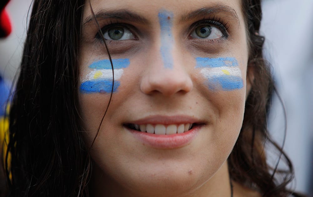 A Soccer fan with her face painted with Uruguay's team colors, watches a live telecast of the group D World Cup match between Uruguay and England, inside the FIFA Fan Fest area on Copacabana beach, in Rio de Janeiro, Brazil.