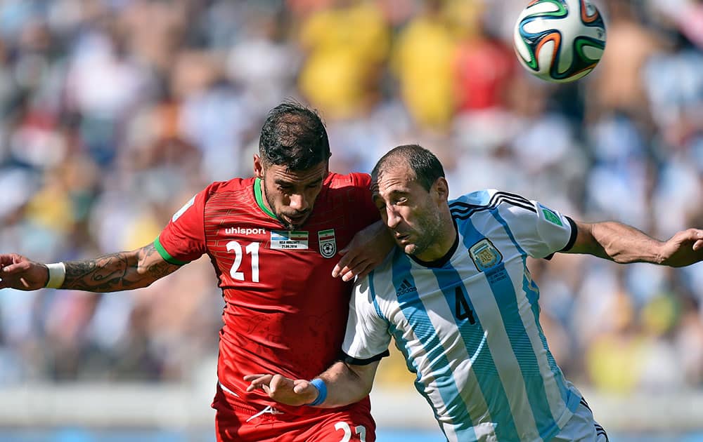 Iran's Ashkan Dejagah heads the ball past Argentina's Pablo Zabaleta during the group F World Cup soccer match between Argentina and Iran at the Mineirao Stadium in Belo Horizonte, Brazil.