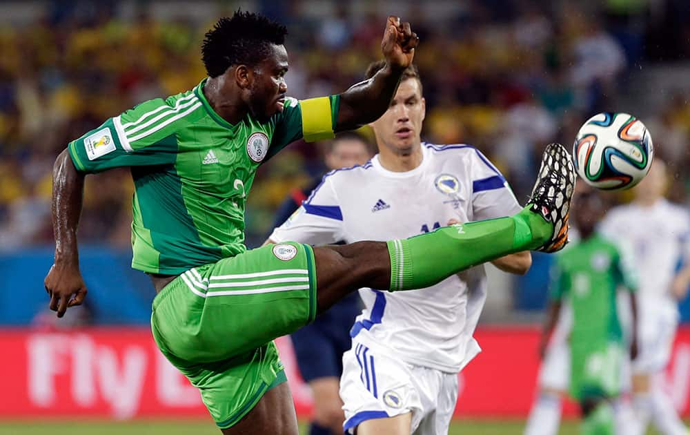 Nigeria's Ejike Uzoenyi clears the ball in front of Bosnia's Edin Dzeko during the group F World Cup soccer match between Nigeria and Bosnia at the Arena Pantanal in Cuiaba, Brazil.