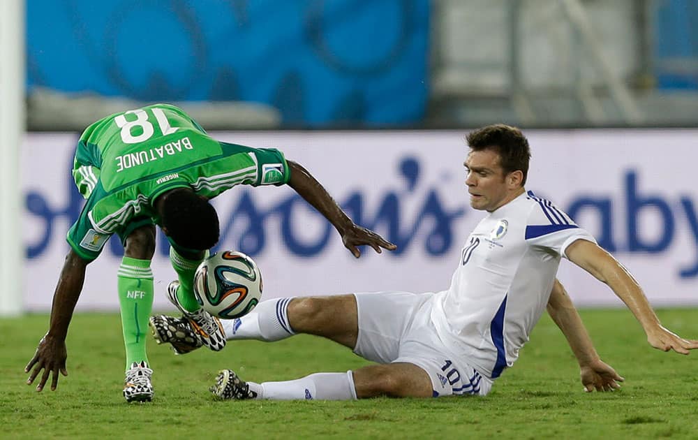 Nigeria's Michael Babatunde, left, and Bosnia's Zvjezdan Misimovic battle for the ball during the group F World Cup soccer match between Nigeria and Bosnia at the Arena Pantanal in Cuiaba, Brazil.