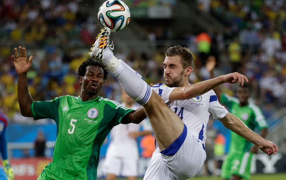 Bosnia's Tino-Sven Susic, right, kicks the ball clear from Nigeria's Efe Ambrose during the group F World Cup soccer match between Nigeria and Bosnia at the Arena Pantanal in Cuiaba, Brazil.