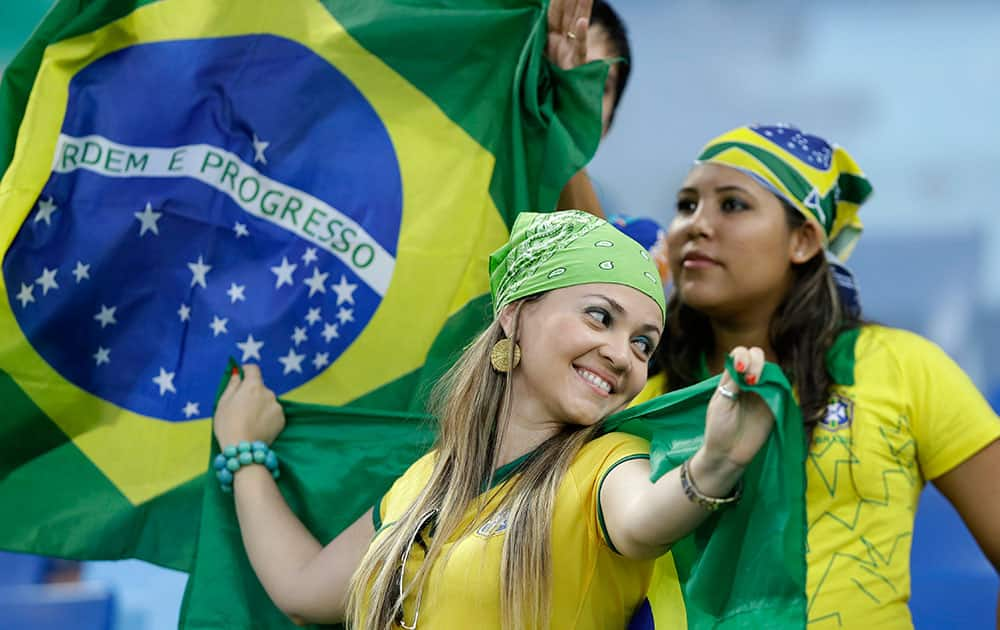 Supporters dressed in the national colours of Brazil and holding a Brazilian flag in the stands before the start of the group F World Cup soccer match between Nigeria and Bosnia at the Arena Pantanal in Cuiaba, Brazil.