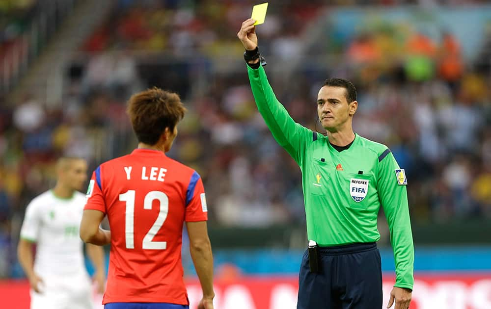 Referee Wilmar Roldan from Colombia shows a yellow card to South Korea's Lee Yong during the group H World Cup soccer match between South Korea and Algeria at the Estadio Beira-Rio in Porto Alegre, Brazil.