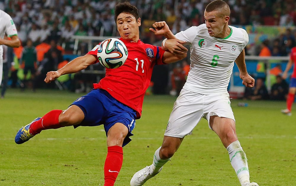 South Korea's Lee Keun-ho (11) kicks at the Algerian goal while being defended by Algeria's Djamel Mesbah (9) during the group H World Cup soccer match between South Korea and Algeria at the Estadio Beira-Rio in Porto Alegre, Brazil.