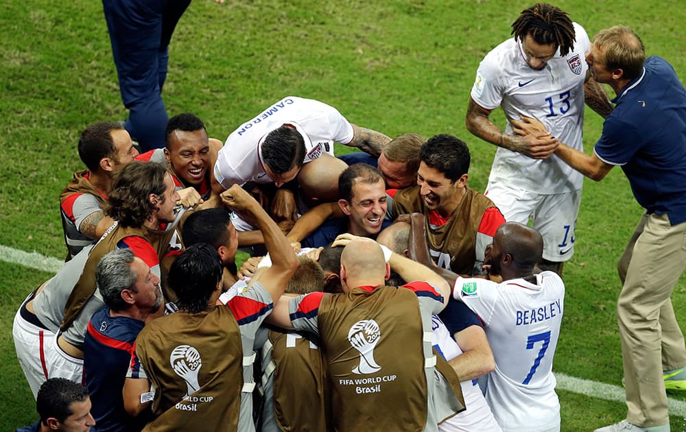 United States' head coach Juergen Klinsmann briefs Jermaine Jones as their team celebrates scoring their second goal during the group G World Cup soccer match between the USA and Portugal at the Arena da Amazonia in Manaus, Brazil. The match ended in a 2-2 draw.